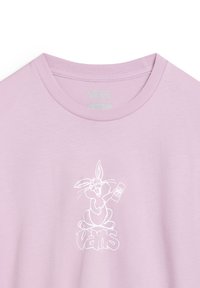 T-shirt en coton rose clair avec un dessin blanc d'un lapin animé tenant une télécommande, avec le texte "VANS" sous l'illustration.