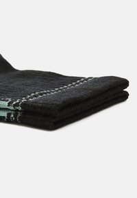 Black towel with a textured surface, folded neatly. Features a contrasting teal accent along the edge, with stitched detailing.