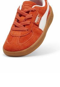 Crvene suede tenisice s bijelim kožnim detaljima, s okruglim vrhom, vezanjem sprijeda i teksturiranom smeđom gumiranom potplatom.