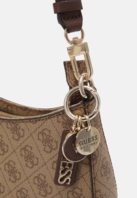 Brun monogrammeret håndtaske med guldfarvet hardware, der har en struktureret overflade, kæde-accent og to mærker med brandnavnet og stiftelsesåret.