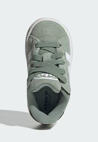 Zelené semišové tenisky s bílými koženými detaily, kulatou špičkou, texturovanou podrážkou a plochými šňůrkami. Na jazyku se nachází logo a polstrovaný límec.