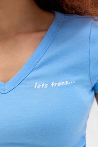 Modrá bavlnená tričko s dizajnom do V a ryhovanou textúrou. Na prednej strane je biele vyšívané text, ktorý znie "iets frans...".