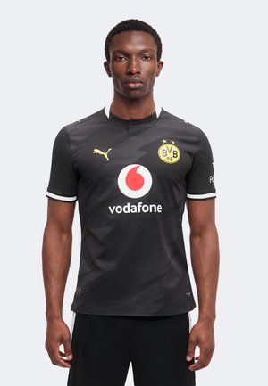 Mand iført sort Borussia Dortmund fodboldtrøje med Vodafone og Puma logoer, stående mod en ensartet lys baggrund, vendt fremad.