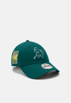 Green baseball cap made of cotton with an embroidered "A's" logo and a patch featuring a player. Curved brim with adjustable back strap.