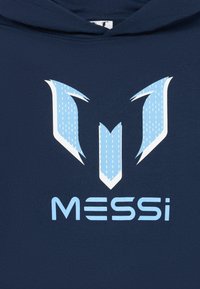 Námornícky mikina s veľkým, stylizovaným svetlo modrým logom nad textom "MESSI" v modernom písme, ktorý vystihuje hladkú štruktúru a odvážny dizajn.