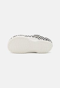 Black and white checkered clogs with a thick white sole and textured grip pattern on the bottom. Adjustable buckle for fit.
