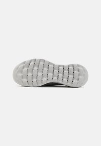 Shoe sole with a textured, flexible white rubber design. Features grooves for traction and a rounded heel for stability.