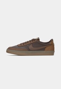 Brown low-top Nike sneaker with suede and leather panels, brown laces, and a translucent gum sole, shown from the side on a white background.