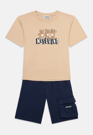 T-shirt beige à manches courtes avec trois ours en peluche et le texte "MOSCHINO" au-dessus d'un short marine avec une poche latérale et le logo "MOSCHINO".