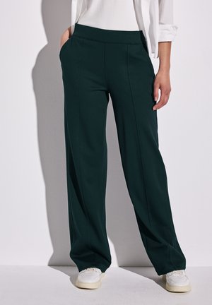 Green wide-leg pants made of soft fabric, featuring side pockets and front seam details, paired with white sneakers.