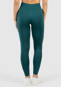 Legginsy w kolorze turkusowym o wysokim stanie, wykonane z elastycznego materiału. Gładka tekstura z dopasowanym krojem, z bezszwowym pasem i długością do kostek.