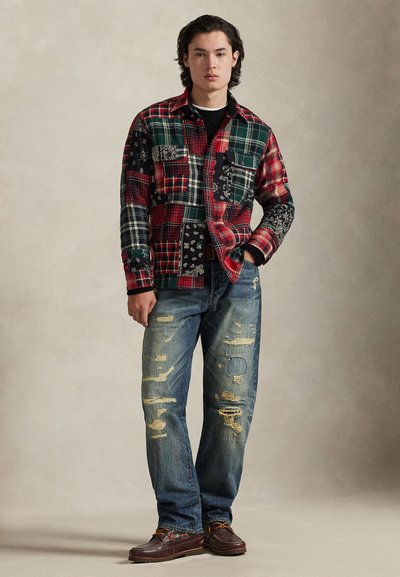 Καρό φανελένιο πουκάμισο με κόκκινα, πράσινα και μαύρα μπαλώματα· μπλε τζιν με φθορές και ελαφριές σκισίματα· καφέ παπούτσια με διακοσμητικά στοιχεία· άνετη γραμμή.