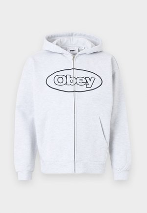 Grijze zip-up hoodie met een trekkoordkap, voorzien van een groot zwart "Obey" logo op de voorkant, kangoeroe pockets en ribbelmanchetten.
