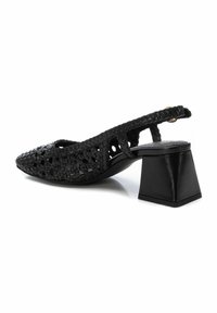 Zapato negro tipo slingback con textura trenzada, punta afilada y tacón de bloque geométrico. Diseñado con detalles recortados en la parte superior.