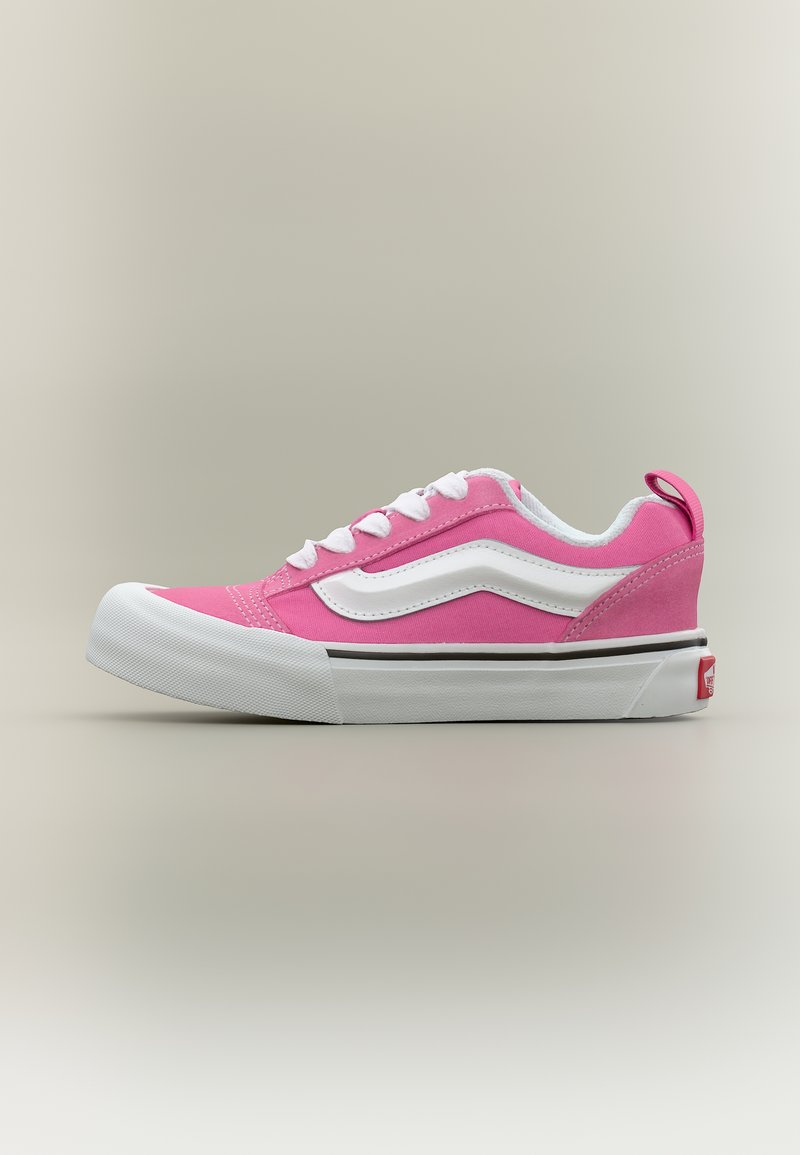 Baskets basses roses avec lacets blancs, une bande blanche sur le côté, une semelle épaisse blanche, et une étiquette logo rouge sur un fond neutre.