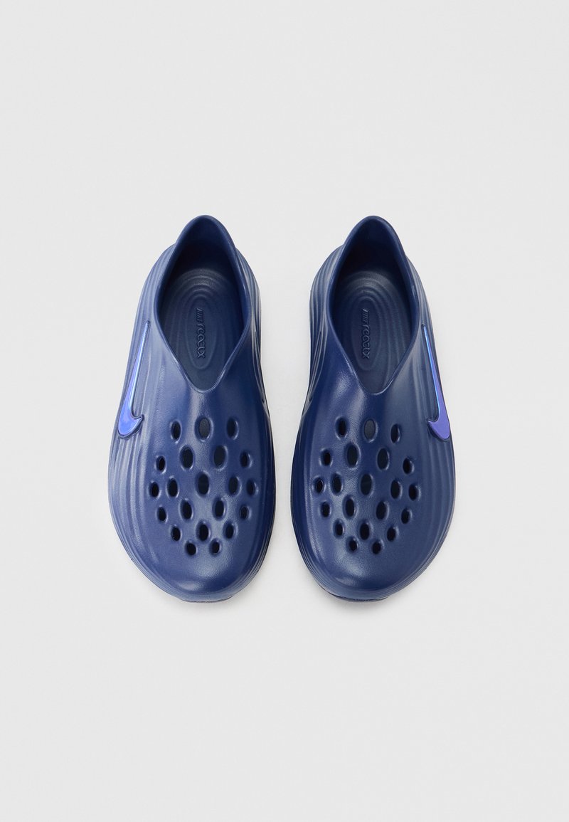 Navy blue slip-on shoes with a smooth plastic texture, featuring numerous ventilation holes and a purple accent on the side.