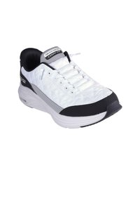 Zapatilla deportiva blanca con diseño de tela acolchada, acentos negros y suela acolchada. Presenta un cierre con cordones y etiqueta de marca en la lengüeta.