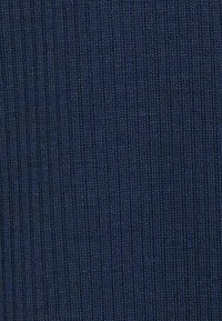 Tessuto a maglia blu scuro con una fine texture a coste verticali, che mostra un dettagliato motivo di tessitura.