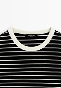 Schwarz-weiß gestreiftes Shirt mit weißen, rundem Halsausschnitt und sichtbarem Markenetikett am Kragen.