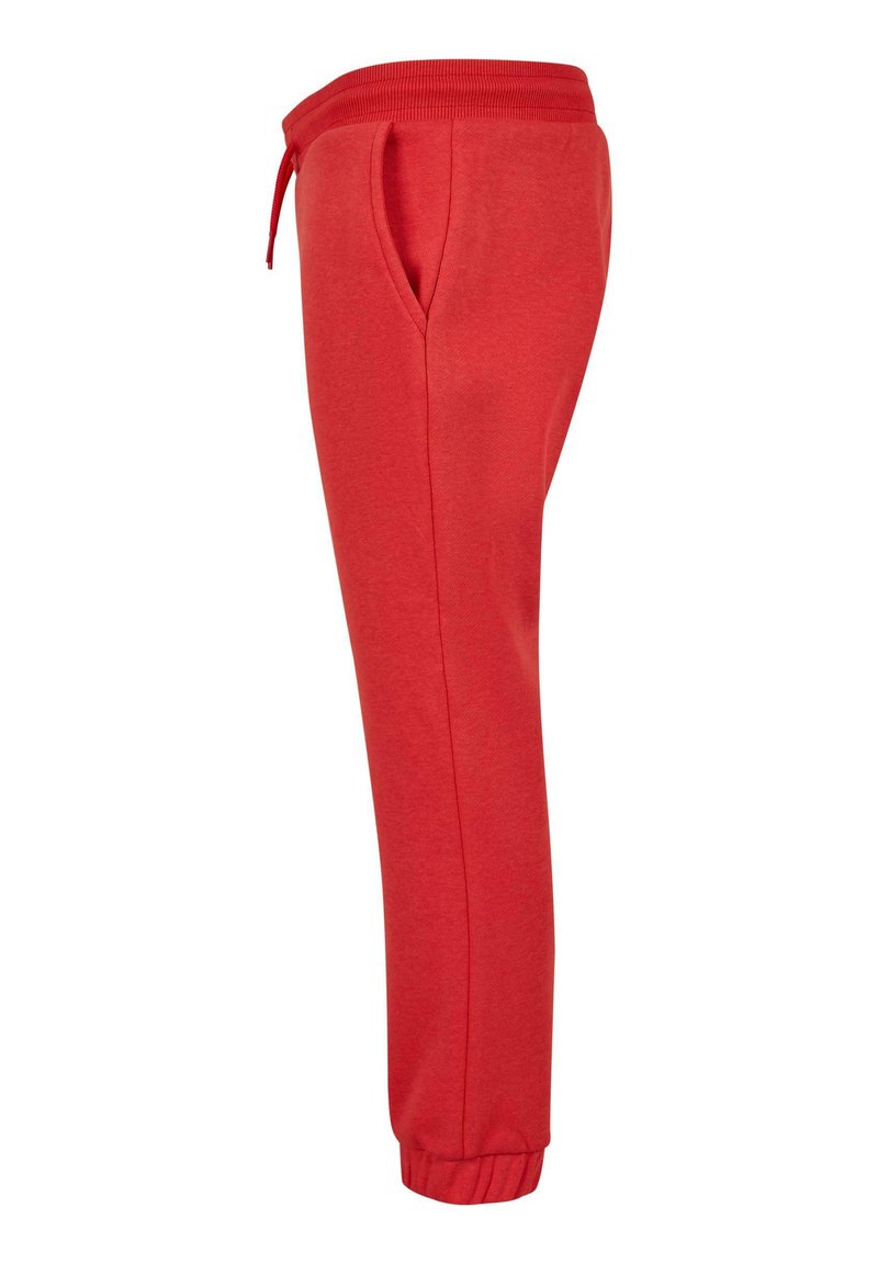 Pantalones de chándal rojos con una cintura acanalada, cuerda ajustable y bolsillos laterales; puños elásticos en los tobillos; tejido suave y texturado.