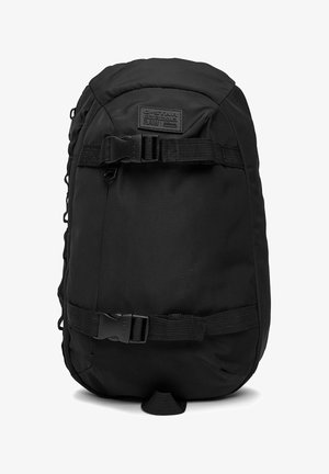 Czarny plecak G-Star RAW z dwoma poziomymi regulowanymi paskami i klamrami z przodu oraz łatką z logo na górze.