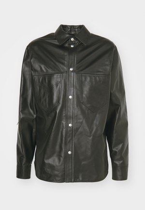 Chaqueta de camisa de cuero negro con cuello, dos bolsillos en el pecho, cierre de botones a presión y detalles de costura en tono. Textura suave.
