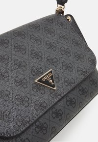 Borsa nera in tessuto con un motivo a logo in rilievo, rifinita con un'emblema di marca triangolare dorato sul davanti e una chiusura magnetica.