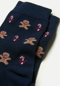 Mørkeblå sokker med strikkede peberkagemænd og slikstokke mønstre. Blød tekstur; har røde og hvide accenter på en mørk baggrund.