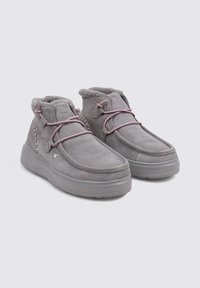 Botas de ante gris hasta el tobillo con un suave forro de piel de borrego, cordones rosas y una suela de goma gruesa y texturizada. Presenta un detalle de costura lateral.