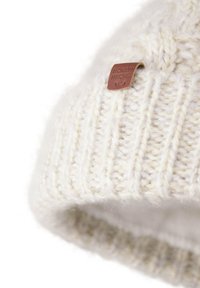 Crème gebreide beanie met geribbelde textuur, voorzien van een bruin leren label. Het ontwerp is omgeslagen bij de manchet voor extra warmte.