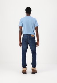 Light blue short-sleeved t-shirt, dark blue jeans, brown boots with tan fuzzy lining, visible back pockets, minimalistic design, no patterns.