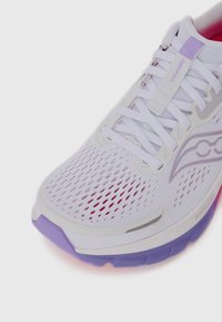 Weißer Laufschuh mit Obermaterial aus Mesh, lila Akzenten und pinken Details an der Sohle. Verfügt über einen gepolsterten Schuhkragen und flache Schnürsenkel für einen sicheren Sitz.