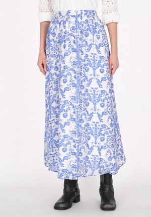 Maxi rok van witte stof met blauwe bloemenprint, voorzien van een geplooide tailleband en knopen aan de voorkant. Gecombineerd met zwarte enkellaarsjes.