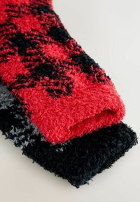 Rot und schwarz gemusterter Strickschal, der über einem dunkelgrauen und schwarzen gemusterten Stück gefaltet ist und ein weiches, flauschiges Material zeigt.