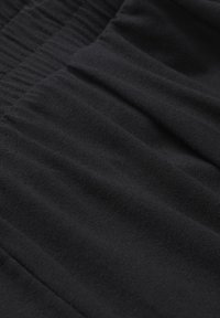 Gros plan de tissu tricoté noir côtelé avec des plis doux et des lignes verticales texturées.