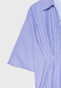 Chemise bleue avec des rayures blanches verticales et des manches courtes larges sur un fond clair uni.