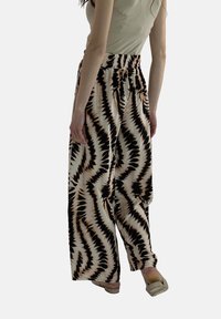 Wijdvallende broek van lichtgewicht stof met een zwart en beige zigzagpatroon. Voorzien van een elastische tailleband en valt losjes.