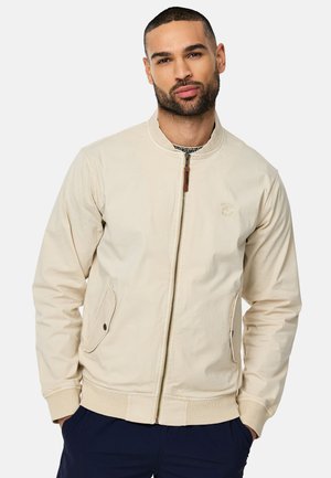 Giacca bomber beige realizzata in tessuto leggero, con chiusura zip, polsini a costine, due tasche laterali e un logo sottile.