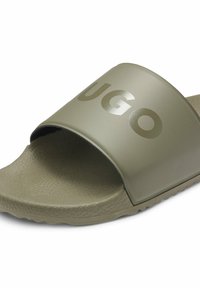 Sandale à glissière vert olive avec semelle texturée et large bride portant le mot "UGO" en grandes lettres.