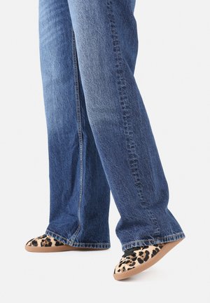 Jeans de denim em lavagem clara a média, combinados com sapatos slip-on de estampa de leopardo, com cabedal de tecido macio e sola de borracha.