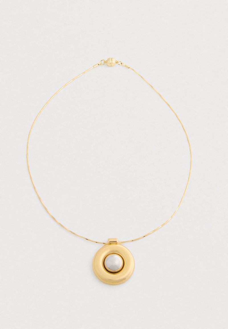 Zlatý náhrdelník s tenkým reťazom a okrúhlym príveskom, ktorý obsahuje centrálny biely perlový kameň na jednoduchom svetlom pozadí.