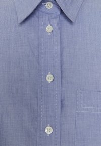 Light purple button-up shirt with a textured fabric, featuring a pointed collar, six buttons, and a pocket on the left side.