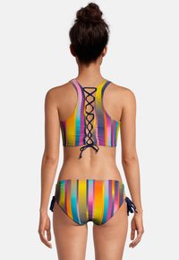 Ensemble de bikini à rayures multicolores avec un dos plongeant et un détail à lacets sur le haut. Le tissu a une texture lisse et des teintes vibrantes.