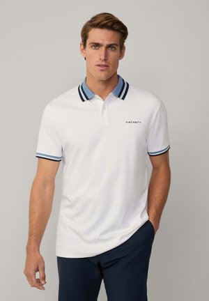 Bijela majica polo s dvobojnim ovratnikom i manžetama s mornarskoplavim i svijetloplavim prugama. Brand logo "HACKETT" na prsima.
