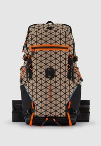Zaino con motivo geometrico in beige e nero, con accenti arancioni. Include molteplici cinghie, cerniere e una tasca laterale.