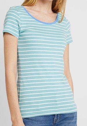 Woman wearing a light blue and white horizontal striped short-sleeve shirt with a rounded blue neckline and blue jeans.