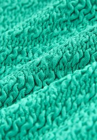 Erineva kangas erksin t�ürkiissinises, lainelise mustriga, tõstetud kiududega, pehme kudumisega, kolmemõõtmeliste lainetega ja siledaga viimistletud.