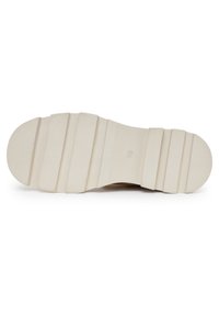 Podeszwa buta o teksturowanym, jasnobeżowym wzorze, z poziomymi rowkami i wypukłościami dla lepszej przyczepności; okrągłe logo wytłoczone w pobliżu środka.
