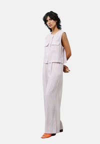 Gestreepte twee-delige outfit bestaande uit een mouwloze top met voorzakken en losse broek. Kleuren zijn wit, blauw en oranje accenten.