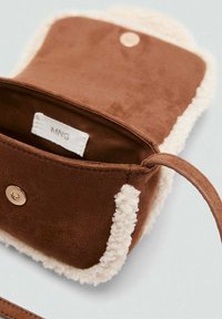 Hnedá zamatová kabelka s krémovým umelým kožuchom, magnetickým zapínaním a jedným ramenným popruhom. Viditeľná vnútorná etiketa.